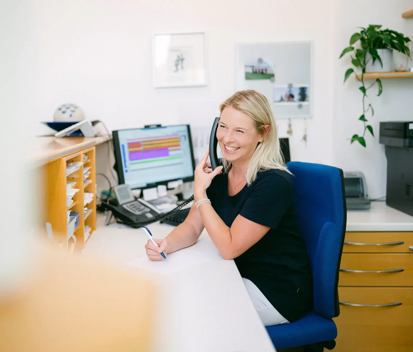 Am Empfang sitzt eine MFA, die gerade mit einem Patienten telefoniert.